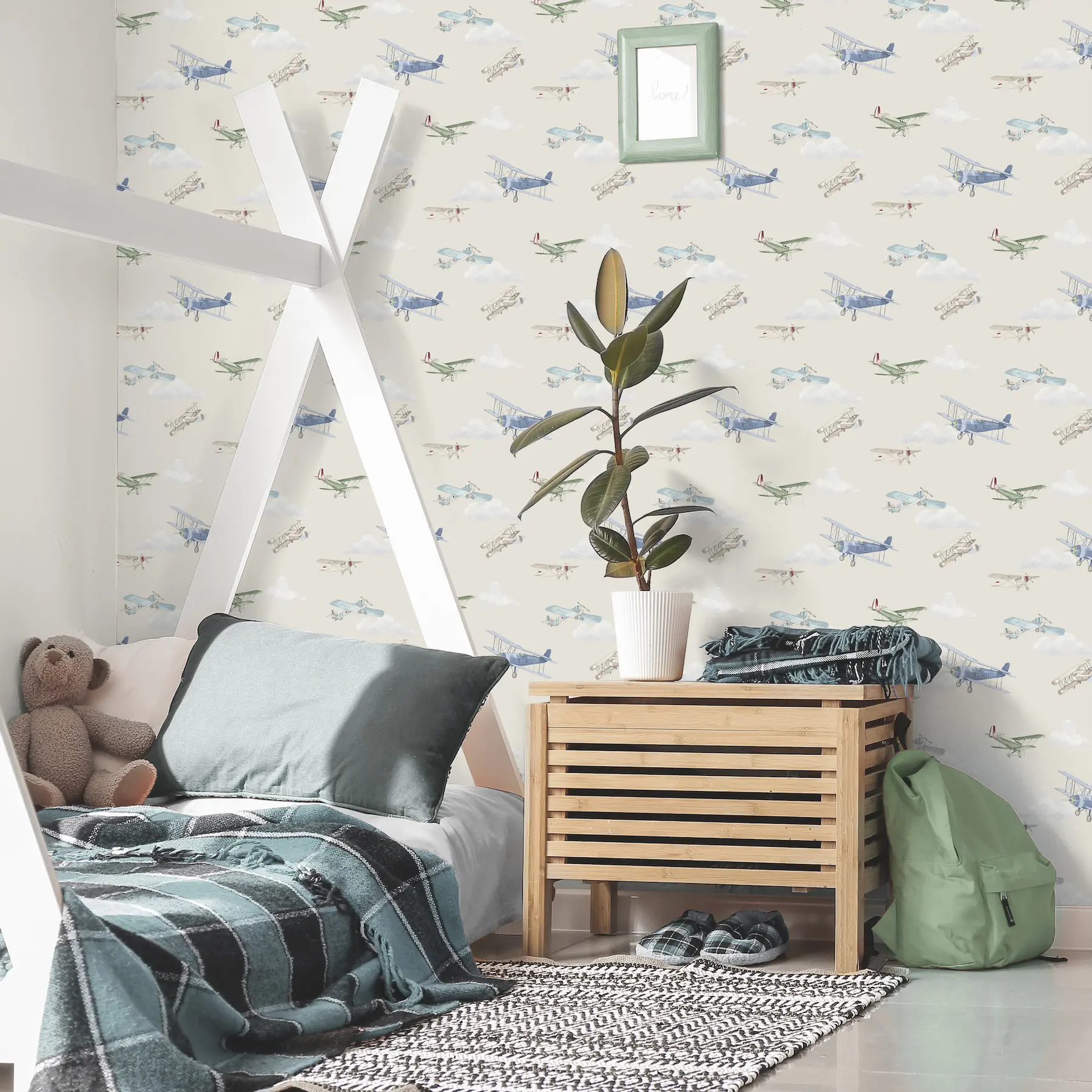 A children's bedroom featuring a playful wallpaper patterned with vintage biplanes flying through soft clouds, styled behind a wooden house-frame bed.