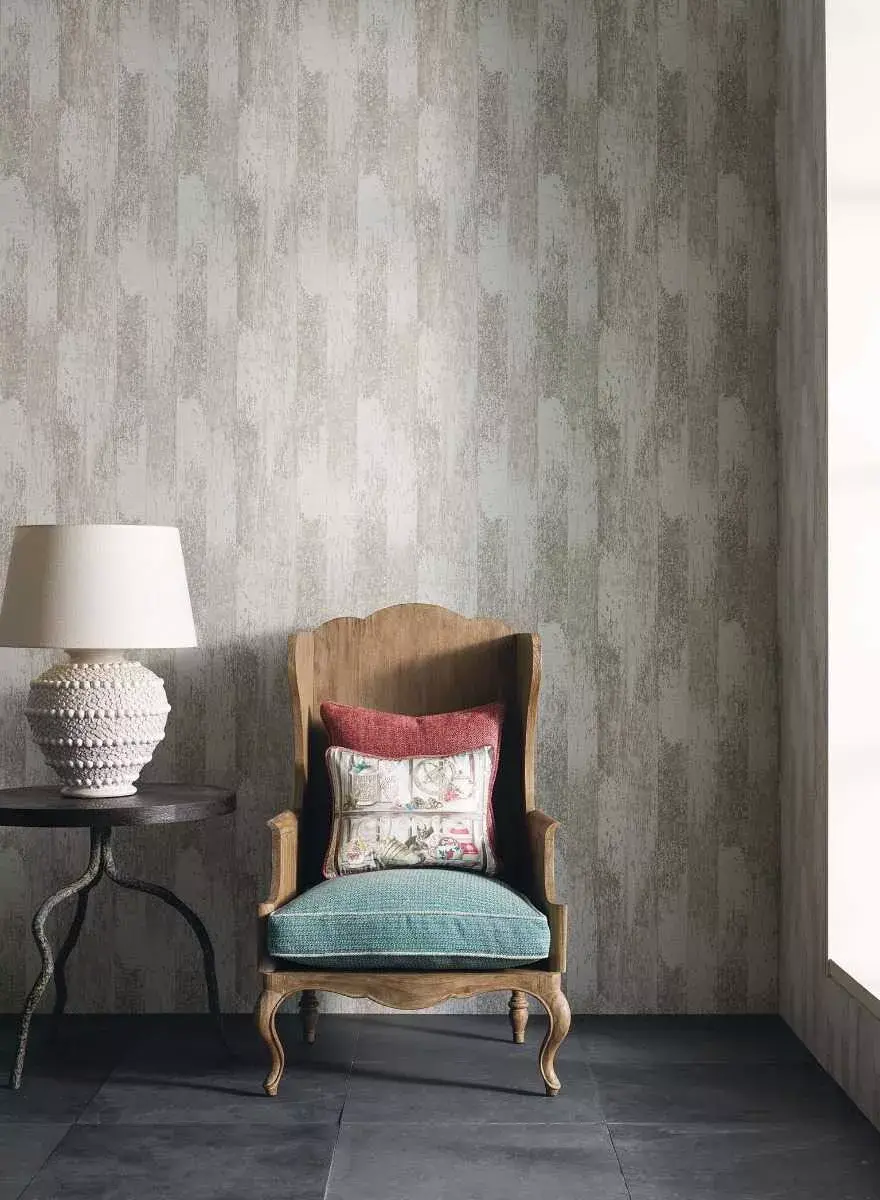 An elegant armchair with a teal cushion sitting against a wall featuring textured, vertical driftwood-patterned wallpaper in muted grey tones.